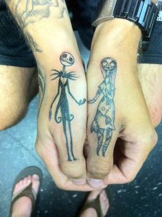 two people holding hands with tattoos on them