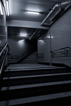 an escalator in a subway station with stairs leading up to the exit door