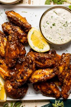 grilled chicken wings with dipping sauce and lemon wedges