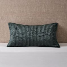 a green pillow sitting on top of a white bed