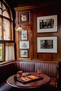 a table with two glasses on it in front of a window filled with framed pictures