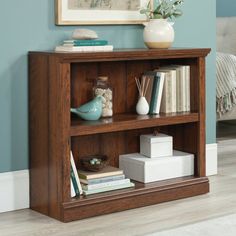 a book shelf with books and vases on it in a room that has blue walls