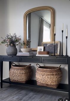 a console table with two baskets and a mirror