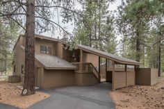 a house in the woods with lots of trees around it and two garages on each side