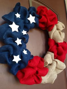 an american flag wreath is hanging on the front door with red, white and blue fabric