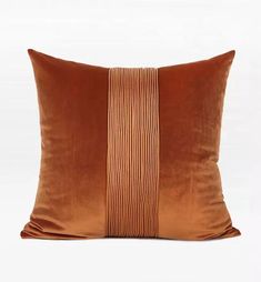 an orange and brown pillow with stripes on the front, sitting against a white background