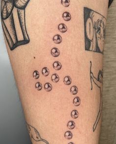 a person with a tattoo on their arm that has beads coming out of the leg