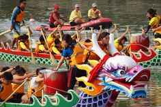 people in dragon boats on the water with paddles and oars, while others row behind them