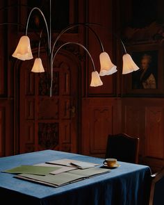 a table with a blue cloth on it and three lamps hanging from the ceiling over it