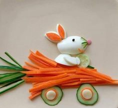 a plate with carrots, cucumbers and an animal made out of food