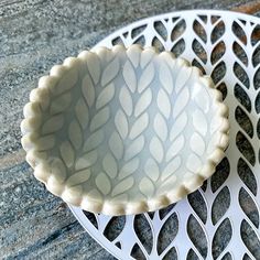 a white bowl sitting on top of a metal grate next to a black and white plate