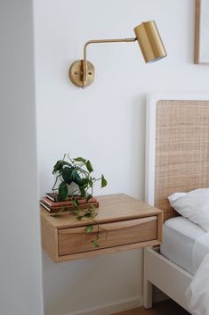 a nightstand with a plant on it next to a bed