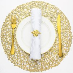 a white plate topped with a gold fork and knife sitting on top of a table