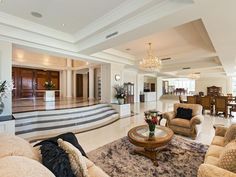 a living room filled with lots of furniture and a chandelier hanging from the ceiling