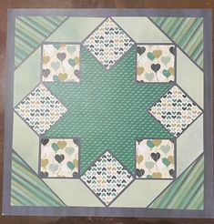 a green and white quilt with hearts on it's center piece in the shape of a star