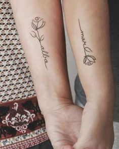 two people holding hands with tattoos on their arms