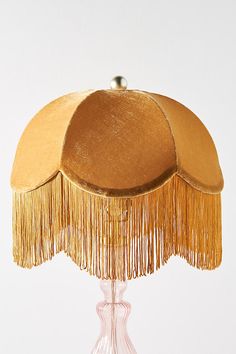 a table lamp with gold fringes on it's base and a white background