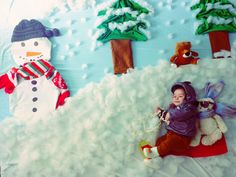 a baby is laying down in front of a snowman and christmas tree scene cake