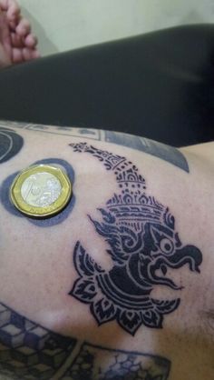 a man with tattoos and a gold coin on his arm