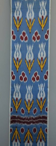 an old blue and yellow cloth with flowers on it hanging from a hook in a wall