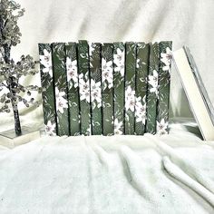 a white tree sitting next to a green and white flowered bookend on top of a bed