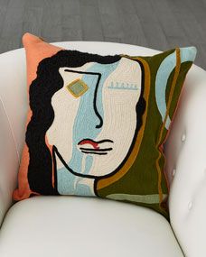 a white chair with a colorful pillow on it's back and a painting on the front