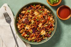 a bowl filled with meat and vegetables next to two bowls of sauces on a table