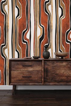 a wooden cabinet with two vases on it in front of a striped wallpaper