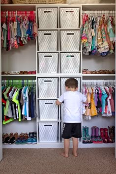 a little boy standing in front of a closet full of clothes