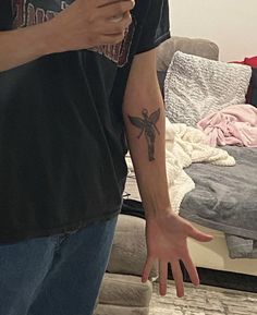 a man with a cross tattoo on his arm holding a cell phone in front of him