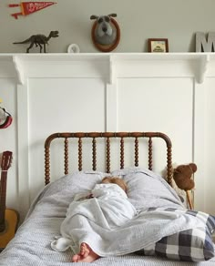 a baby is sleeping in his bed under a blanket and stuffed animals are on the wall above him