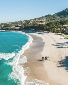 people are walking along the beach near the ocean