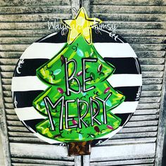 a green christmas tree painted on the side of a building with words be merry written in black and white