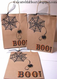 three brown bags decorated with spider webs and words boo or ooo on them