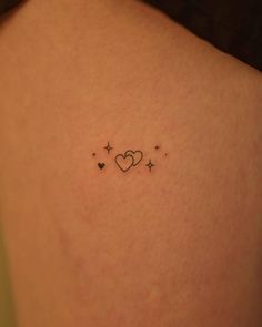 a small heart and stars tattoo on the back of a woman's shoulder