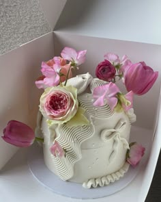 there is a white cake with pink flowers on it