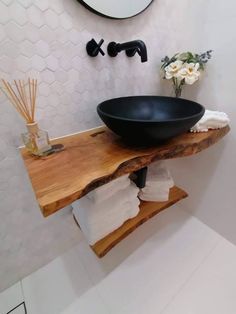 a black bowl sink sitting on top of a wooden counter next to a white wall