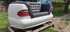 the back end of a white car with black leather seats on a dolly in front of a house