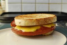 a grilled cheese and tomato sandwich sitting on top of a white plate next to a black tray