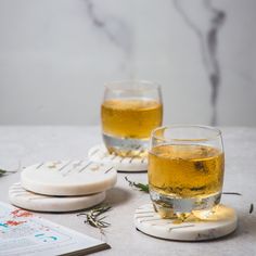 two glasses of beer sitting on top of a table next to papers and coasters