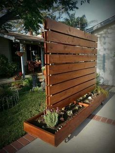 a wooden planter with succulents in it on the side of a house