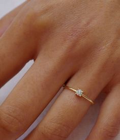 a woman's hand with a diamond ring on top of her finger and the other hand holding it