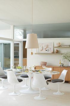 an image of a dining room setting with white chairs and round table in the middle