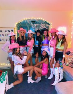 a group of women dressed in costumes posing for a photo with one woman wearing pink cowboy hats