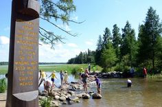 several people are standing on rocks in the water near a sign that says welcome to the oregon wilderness