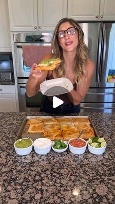 a woman holding a plate with food on it in front of some bowls and plates