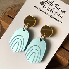 a pair of blue and gold earrings sitting on top of a white piece of paper