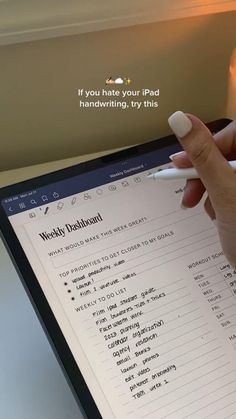 a woman's hand holding a pen over a tablet