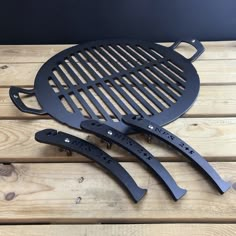 two barbecue grates sitting on top of a wooden table next to another grilling pan