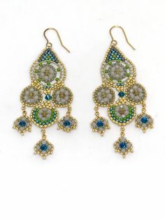 two pairs of earrings with green and blue beading on them, one is hanging from the